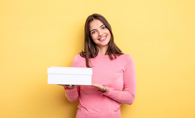 Mulher bonita sorrindo alegremente, sentindo-se feliz e mostrando um conceito. conceito de embalagem de caixa branca