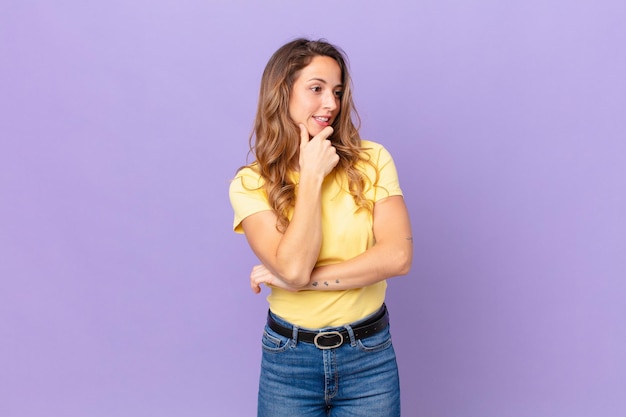 Mulher bonita sorrindo com uma expressão feliz e confiante com a mão no queixo