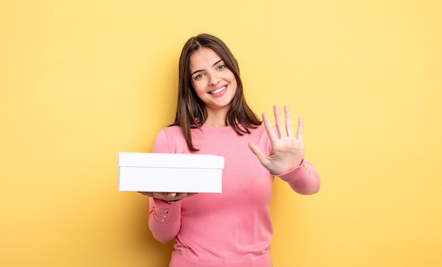 Mulher bonita sorrindo e parecendo amigável mostrando o conceito de embalagem de caixa branca número cinco