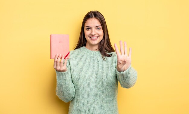 Mulher bonita sorrindo e parecendo amigável mostrando o conceito de planejador número quatro