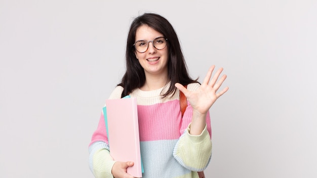 Mulher bonita sorrindo e parecendo amigável, mostrando o número cinco. conceito de estudante universitário