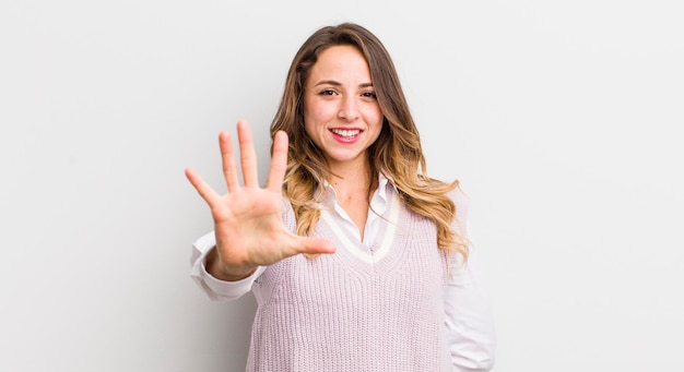 Mulher bonita sorrindo e parecendo amigável mostrando o número cinco ou quinto com a mão em contagem regressiva