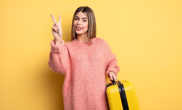 mulher bonita sorrindo e parecendo amigável, mostrando o número dois. conceito de viagem de mala