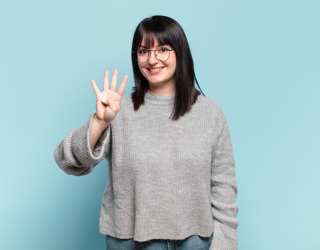 Mulher bonita sorrindo e parecendo amigável, mostrando o número quatro ou o quarto com a mão para a frente, em contagem regressiva