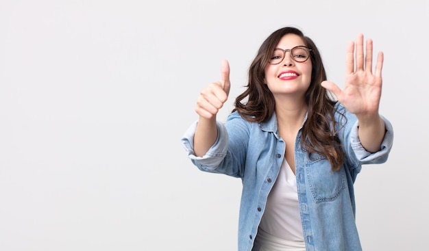 Mulher bonita sorrindo e parecendo amigável, mostrando o número seis ou sexto com a mão para a frente, em contagem regressiva