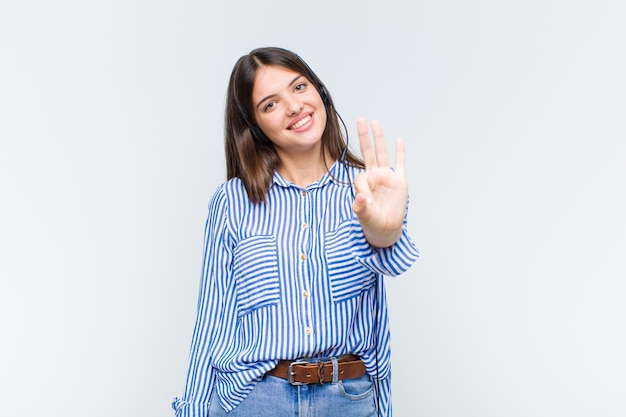 Mulher bonita sorrindo e parecendo amigável, mostrando o número três ou terceiro com a mão para a frente, em contagem regressiva