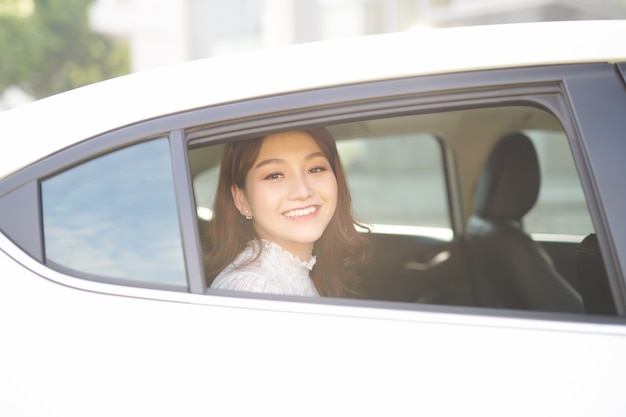 Mulher bonita sorrindo enquanto está sentado no banco de trás do carro. A senhora está olhando pela janela.