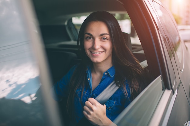 Mulher bonita sorrindo enquanto está sentado no banco de trás do carro