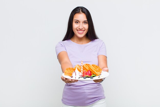 Mulher bonita sorrindo feliz com um olhar amigável, confiante e positivo, oferecendo e mostrando um objeto ou conceito