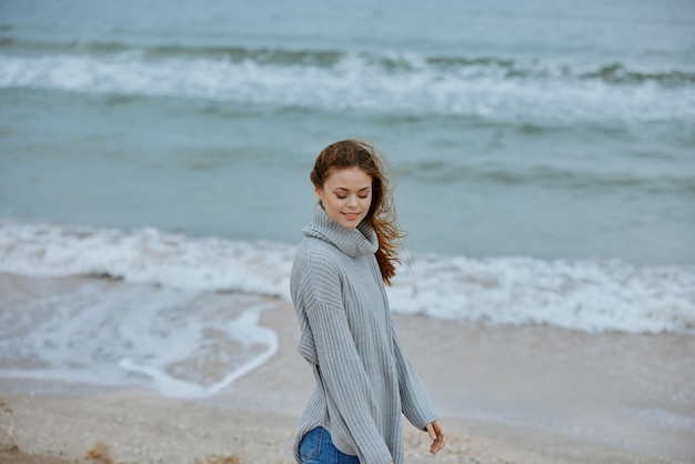 Mulher bonita sozinha ao lado do oceano, tempo nublado, mulher feliz relaxando, foto de alta qualidade.