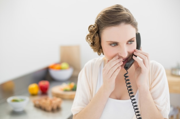 Mulher bonita telefonando com o telefone dela na cozinha