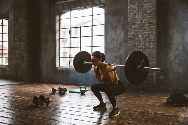 Mulher bonita treinando e fazendo exercícios funcionais na academia