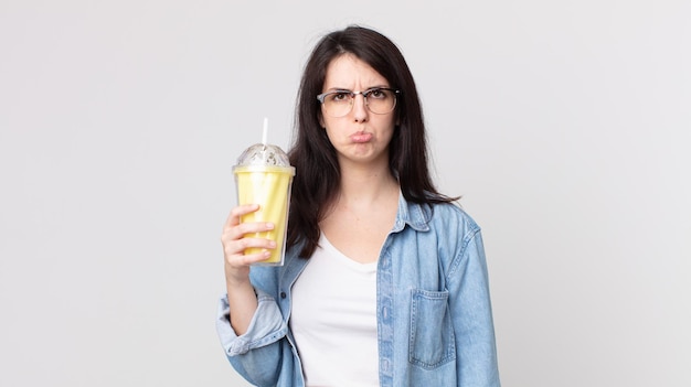 Mulher bonita triste e chorona com um olhar infeliz, chorando e segurando um milkshake de baunilha