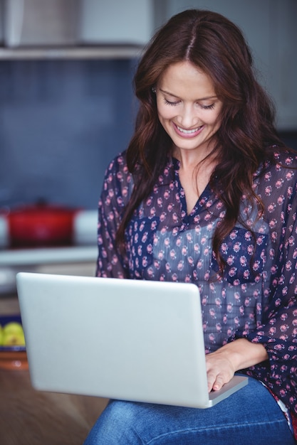 Mulher bonita usando um laptop na cozinha