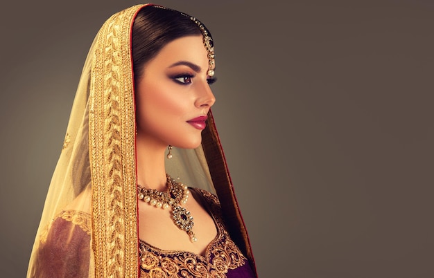 Mulher bonita vestida com uma blusa indiana tradicional e dupatta de xale de cabeça coberto com borda dourada