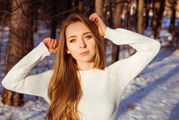 Mulher bonita vestindo um suéter branco na floresta de inverno