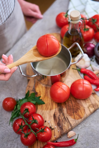 Mulher branqueando um tomate segurando a panela com água quente para descascar ainda mais