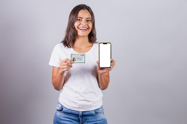 Foto mulher brasileira com carteira de identidade brasileira documento rg smartphone tela branca para propagandas