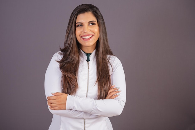 Mulher brasileira de foto horizontal com jaleco médico nutricionista com os braços cruzados