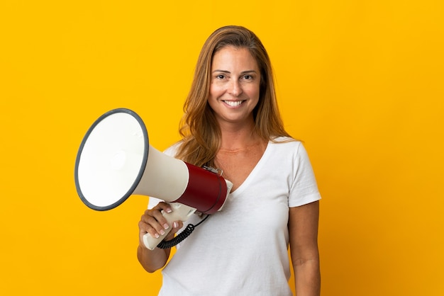 Foto mulher brasileira de meia-idade isolada segurando um megafone e sorrindo muito