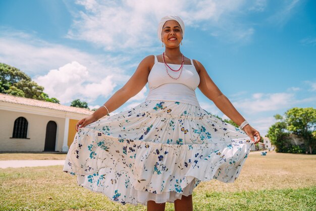 Mulher brasileira feliz descendente vestida com o tradicional traje baiano e dançando