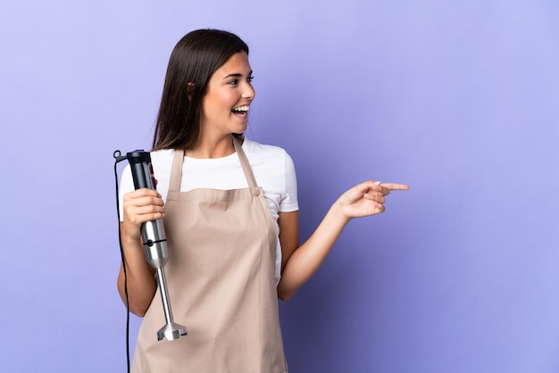 Mulher brasileira usando varinha mágica isolada na parede roxa apontando o dedo para o lado e apresentando um produto