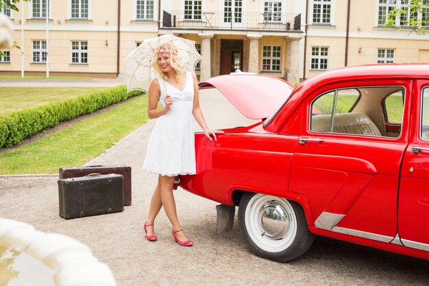 Foto mulher brilhante e feliz com carro retrô vermelho