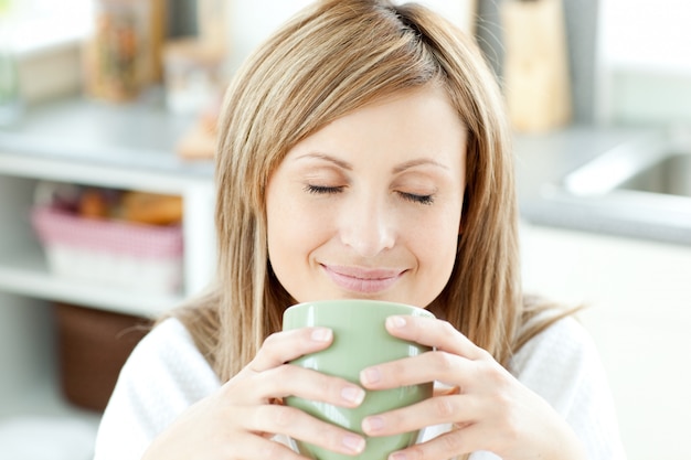 Mulher brilhante segurando uma xícara de café na cozinha