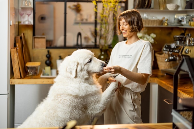 Mulher brinca com seu cachorro na cozinha de casa