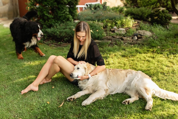 Foto mulher brincando com o cachorro labrador e sennenhund ao ar livre em um parque verde