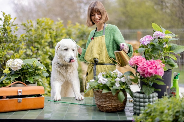 Mulher brincando com seu cachorro branco enquanto cuida de flores no jardim