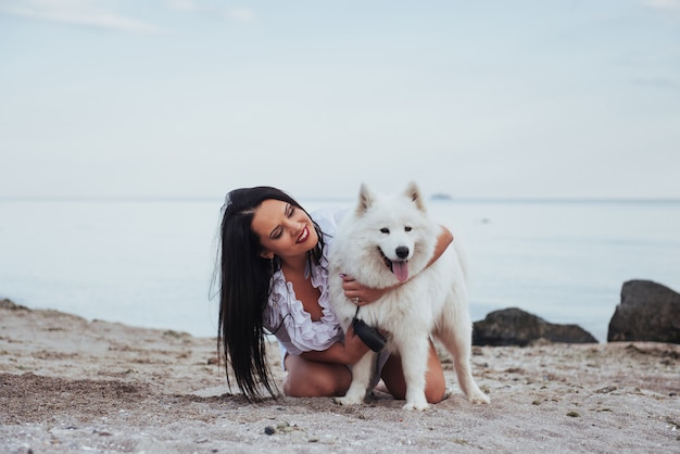 Mulher brincando com seu cachorro na praia