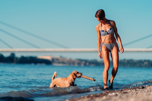 Mulher brincando com um cachorro à beira do rio