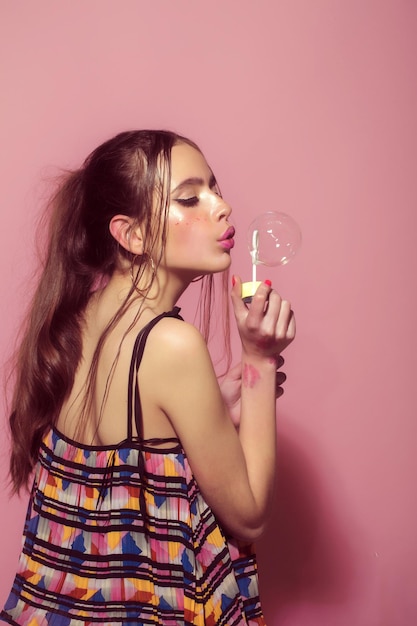 Mulher brincar com soprador de bolha de balão de sabão na mão de menina modelo com maquiagem glamour e hai ...
