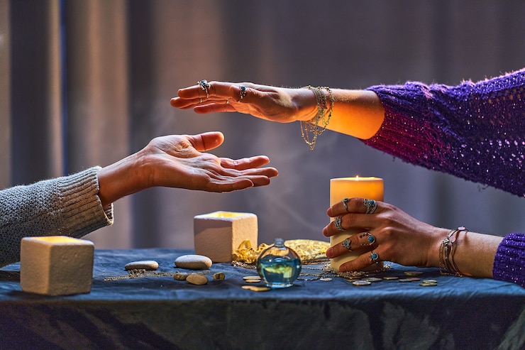 Foto mulher bruxa cigana durante o ritual de quiromancia e adivinhação em torno de velas e outros acessórios mágicos. ilustração mágica