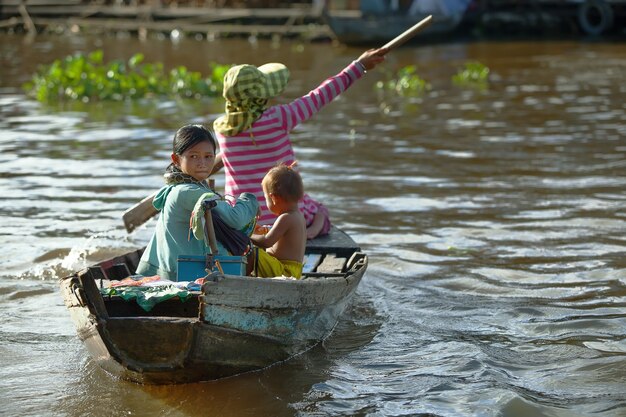 Mulher cambojana e duas crianças na aldeia inundada em Siem Reap, Camboja