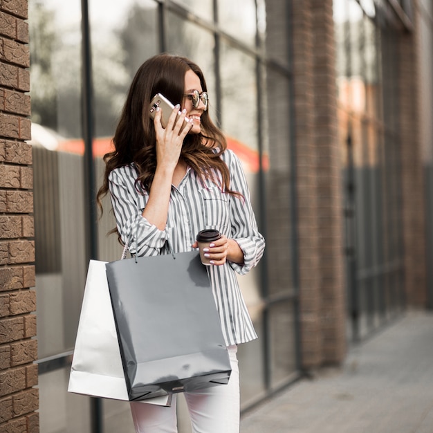 Mulher caminha depois das compras e usa o telefone.