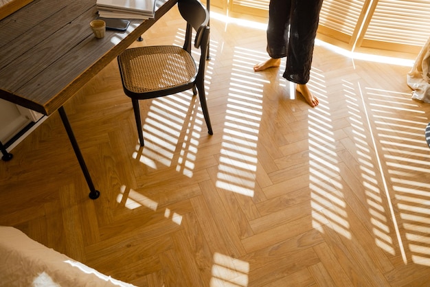 Mulher caminha no parquet de madeira em casa