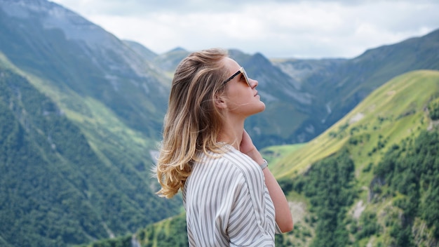 Mulher, caminhadas nas montanhas na hora do dia ensolarado. vista de kazbegi, geórgia