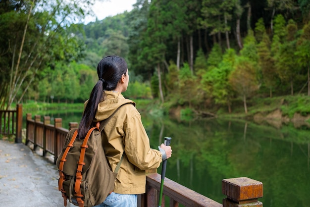 Foto mulher caminhando ao longo da margem do lago na trilha da floresta