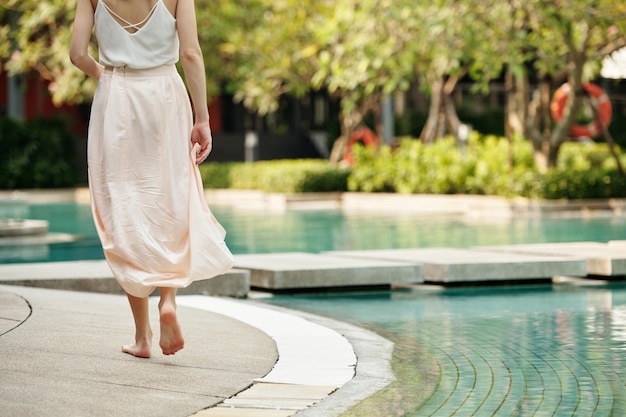 Mulher caminhando ao longo da piscina ao ar livre