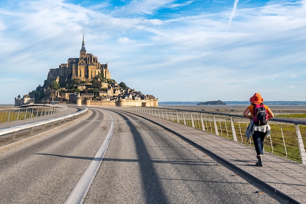 Mulher caminhando em direção ao Mont Saint Michel