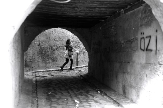 Foto mulher caminhando na calçada contra a parede vista do túnel