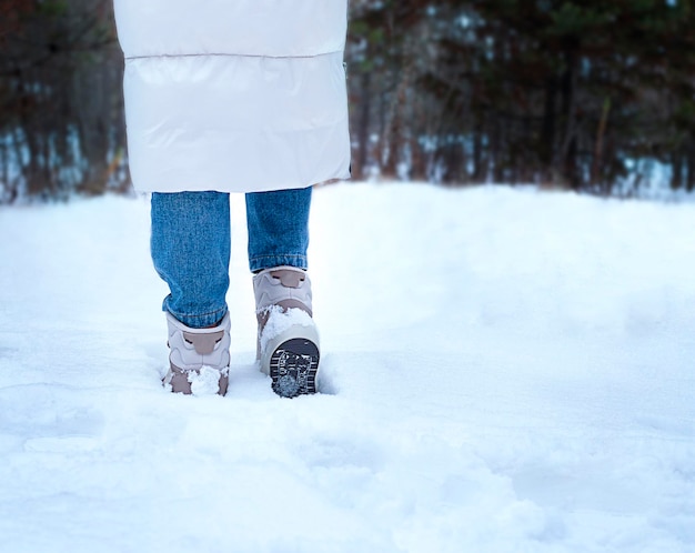 Mulher caminhando na floresta de inverno close de pernas e botas