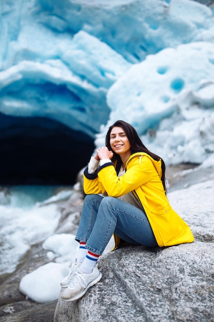 Mulher caminhando na geleira gosta de liberdade Turista de jaqueta amarela perto de grande geleira