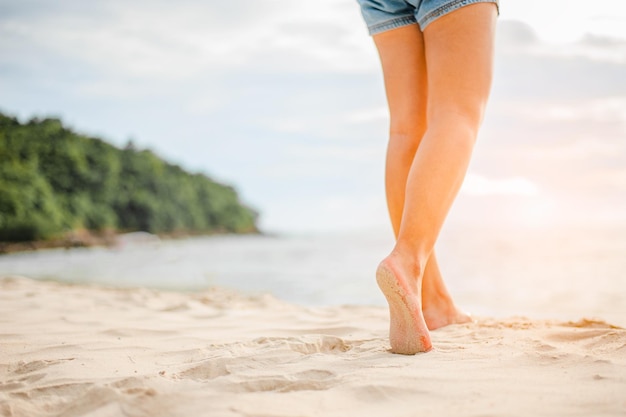 Mulher caminhando na praia ao pôr do sol