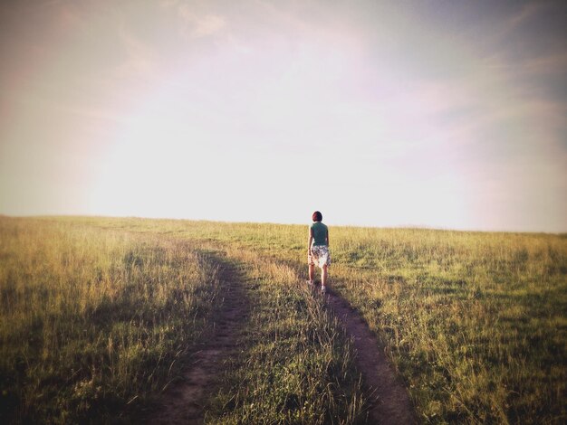 Mulher caminhando no campo contra o céu