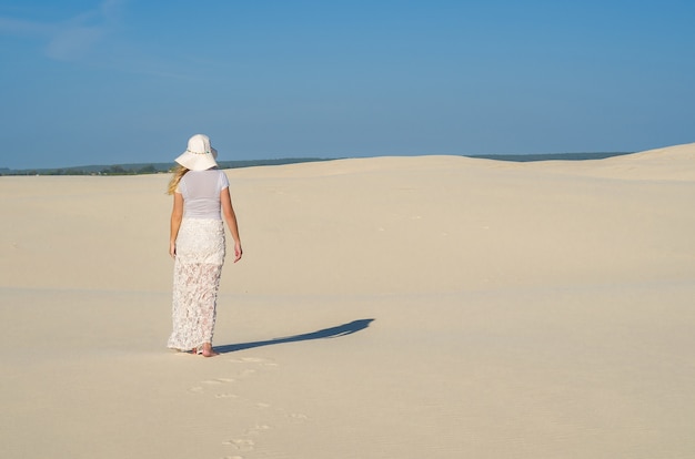 Mulher caminhando no deserto de dunas