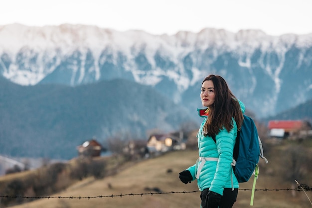 Foto mulher caminhando no inverno e admirando a vista incrível em direção às montanhas na luz do pôr-do-sol