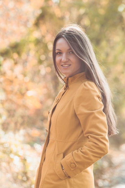 Mulher caminhando no parque outonal com casaco amarelo